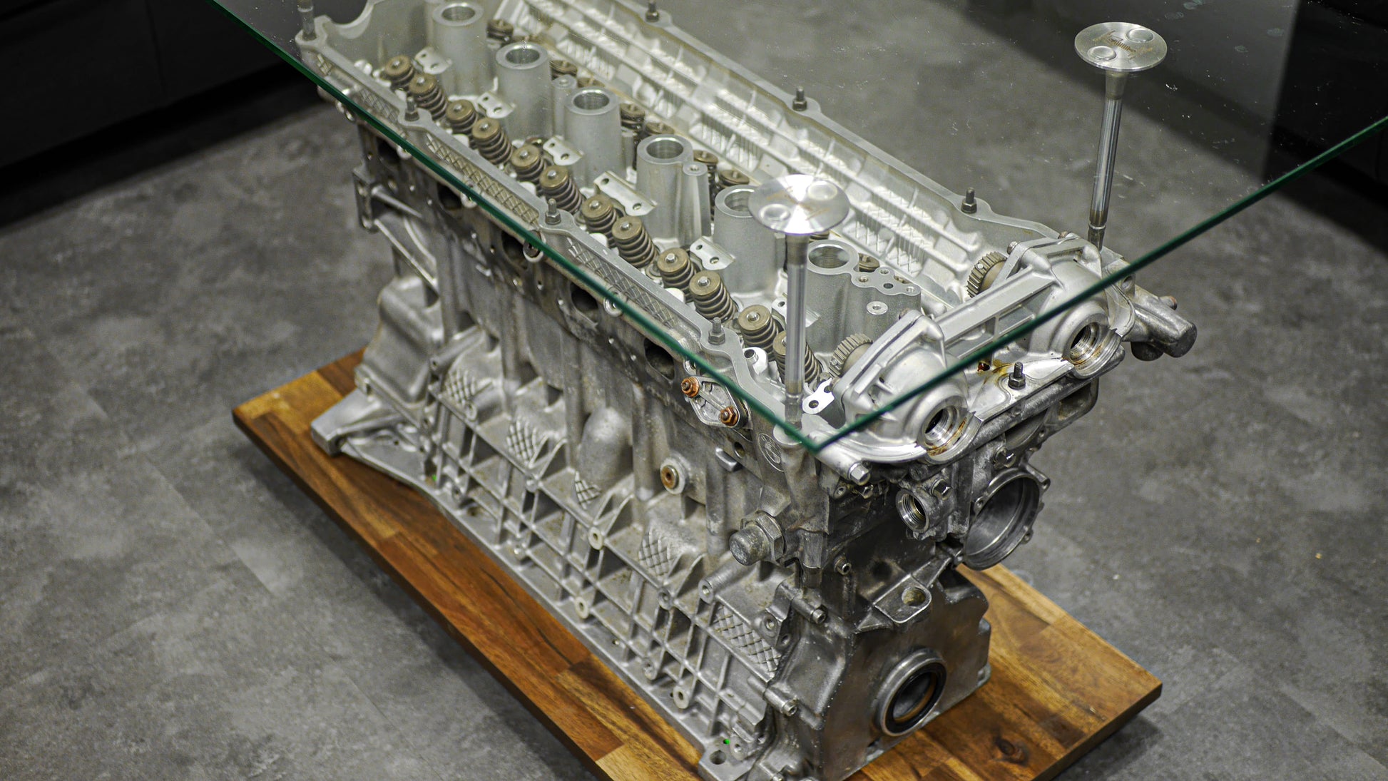 Motorblock-Tisch von BMW als Couchtisch in der Farbe Silber. Tisch aus Autoteilen mit Detailaufnahme der Zylinderköpfe und Ventilen als Halterung.