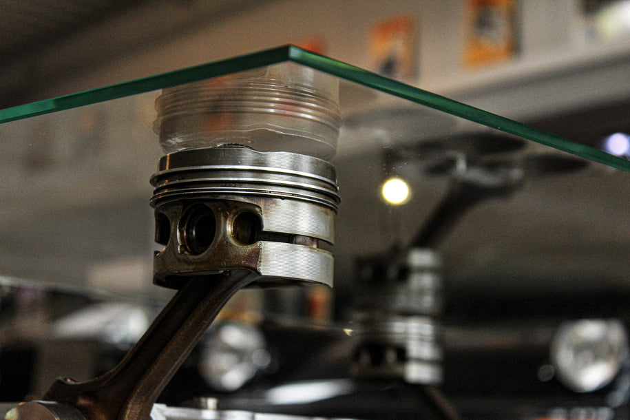 Detailansicht des Motorblock Tischs – originale BMW Kolben als stilvolle Trageelemente, kombiniert mit gehärteter Glasplatte für ein einzigartiges Design