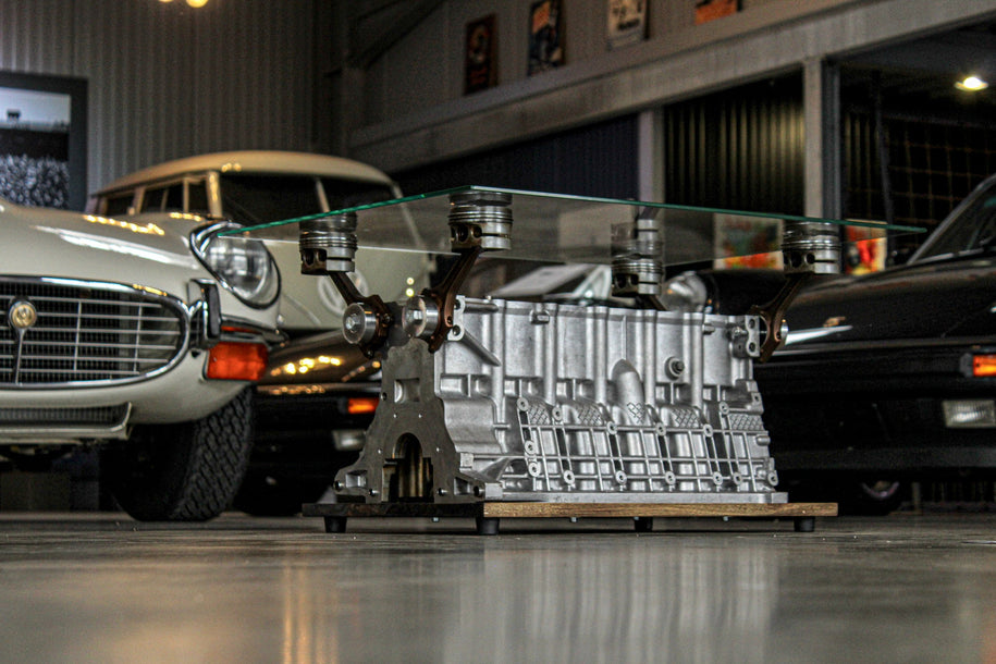 Motorblock Tisch aus BMW Motor in einem Showroom mit klassischen Fahrzeugen – Upcycling-Möbel im Motorsport-Stil für Auto-Liebhaber